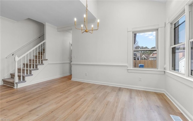 unfurnished dining area with baseboards, visible vents, stairway, wood finished floors, and an inviting chandelier