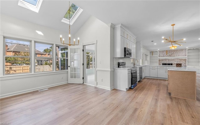 kitchen with a healthy amount of sunlight, stainless steel appliances, a notable chandelier, and open floor plan