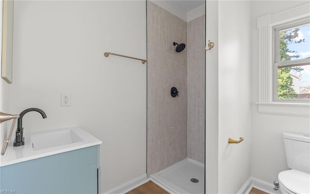 full bathroom featuring toilet, baseboards, a sink, and tiled shower