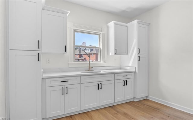 interior space with white cabinetry, light countertops, and a sink