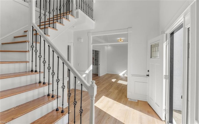 entryway featuring stairway, a high ceiling, visible vents, and wood finished floors