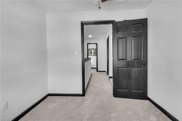 spare room featuring light carpet and baseboards