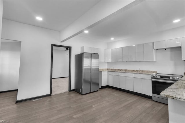 kitchen with stainless steel appliances, recessed lighting, light stone counters, and wood finished floors