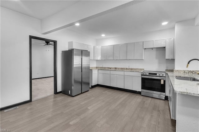 kitchen with light wood finished floors, stainless steel appliances, recessed lighting, a sink, and light stone countertops