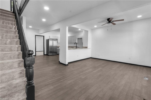 unfurnished living room featuring baseboards, stairway, dark wood finished floors, and recessed lighting