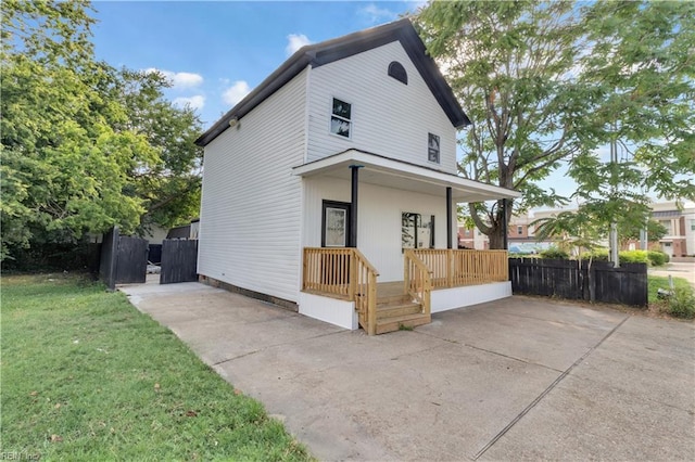 view of front of home featuring a porch, fence, and a front lawn