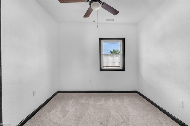 carpeted empty room with a ceiling fan and baseboards