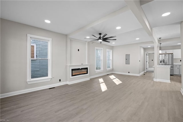 unfurnished living room featuring visible vents, light wood-style floors, baseboards, electric panel, and a glass covered fireplace