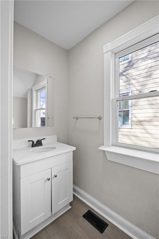 bathroom with baseboards, visible vents, wood finished floors, and vanity