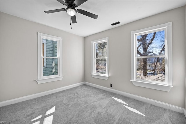 carpeted spare room with baseboards, visible vents, and ceiling fan