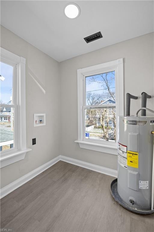 utility room featuring electric water heater and visible vents