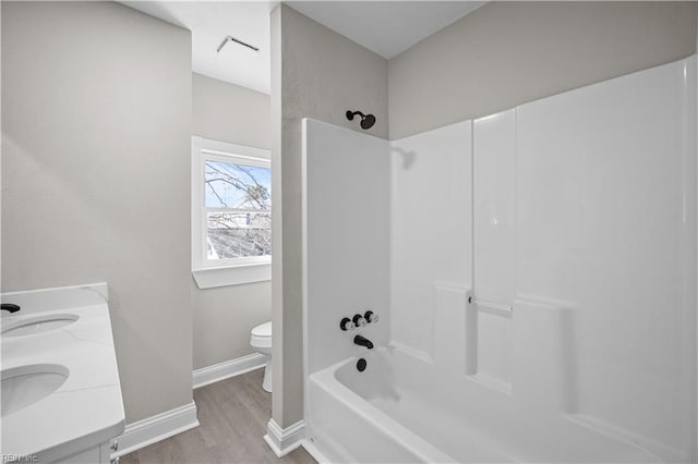 full bath with double vanity, baseboards, toilet, wood finished floors, and shower / bathing tub combination