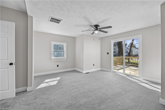 unfurnished room with carpet floors, visible vents, and baseboards