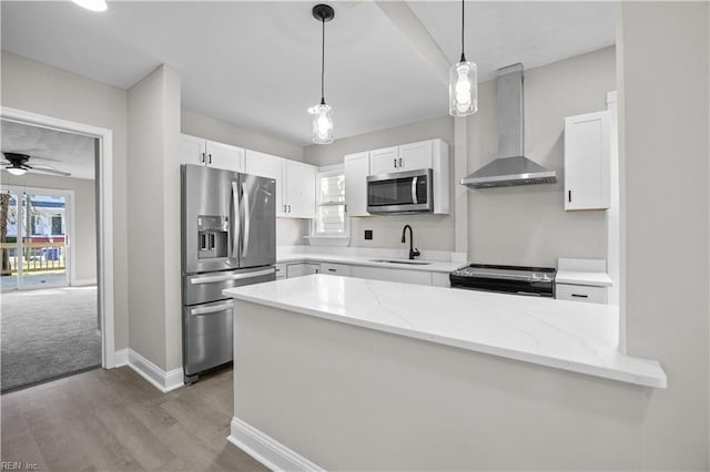 kitchen featuring wall chimney exhaust hood, appliances with stainless steel finishes, a sink, and a healthy amount of sunlight