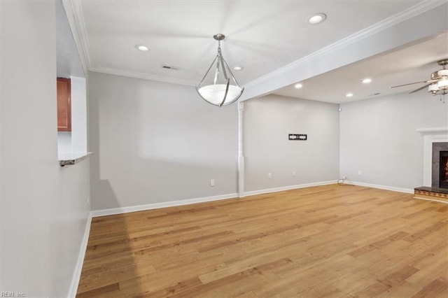 unfurnished living room with ornamental molding, recessed lighting, light wood-style flooring, and a lit fireplace