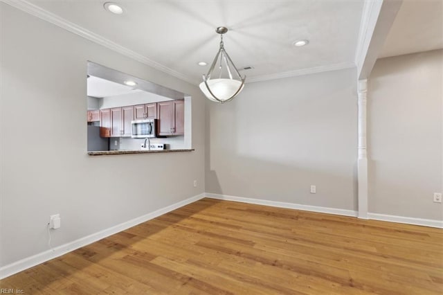 unfurnished dining area with light wood-style floors, baseboards, crown molding, and recessed lighting