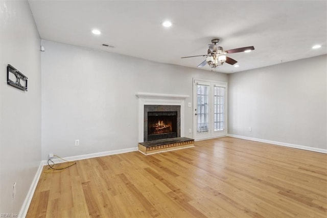 unfurnished living room with light wood-type flooring, a lit fireplace, baseboards, and recessed lighting