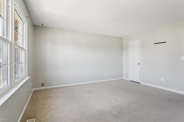 empty room with carpet, plenty of natural light, visible vents, and baseboards