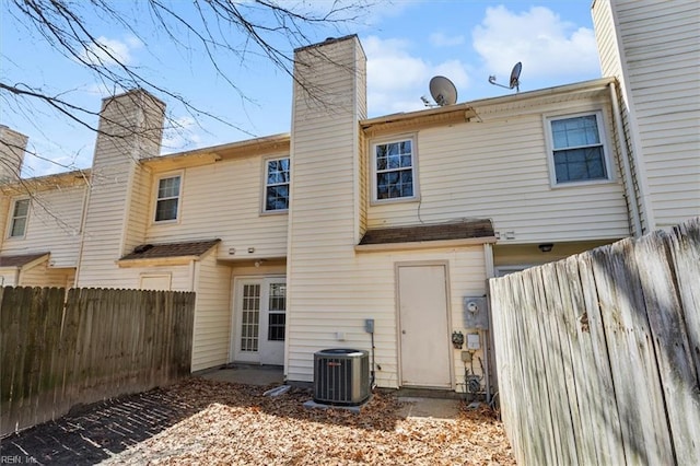 back of property featuring cooling unit, fence, and a chimney