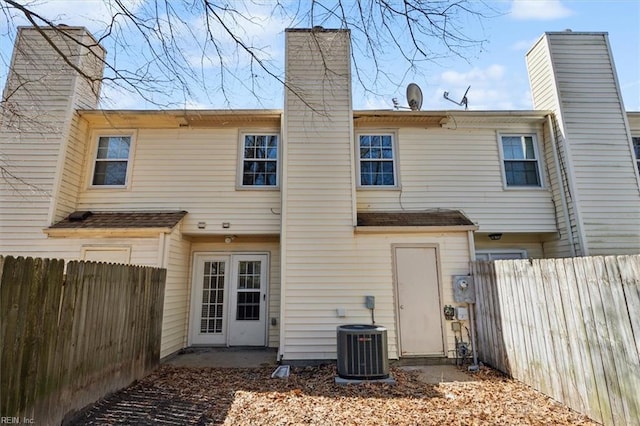 rear view of house with central AC, a chimney, and a fenced backyard