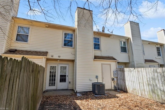 rear view of house with a chimney, fence, and central AC