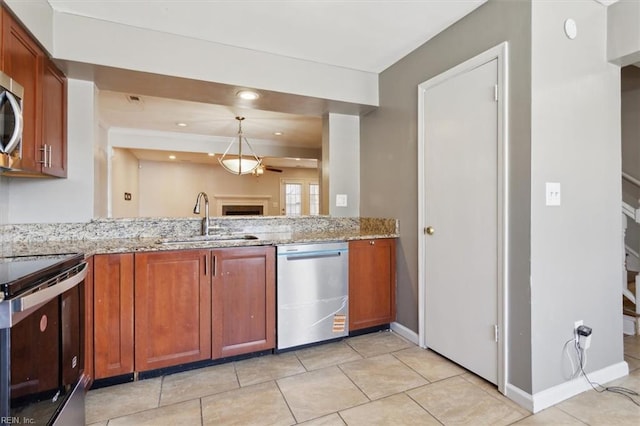 kitchen featuring brown cabinetry, appliances with stainless steel finishes, light stone countertops, pendant lighting, and a sink