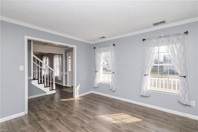 empty room featuring stairs, a wealth of natural light, wood finished floors, and visible vents