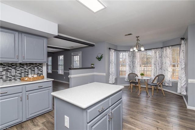 kitchen with backsplash, gray cabinets, wood finished floors, and light countertops