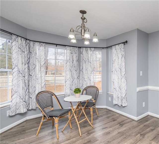 dining area featuring wood finished floors, baseboards, and an inviting chandelier