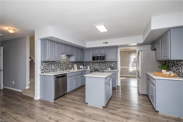 kitchen with gray cabinetry, light countertops, appliances with stainless steel finishes, a center island, and light wood finished floors