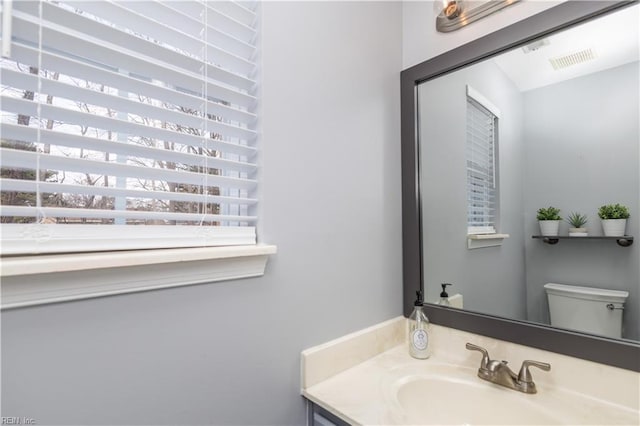 half bath with visible vents, vanity, and toilet