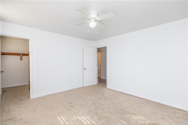 unfurnished bedroom with a closet, carpet flooring, a walk in closet, and baseboards