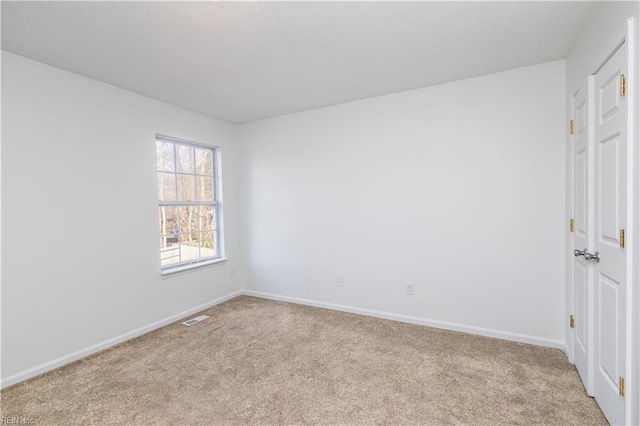 carpeted empty room with visible vents and baseboards