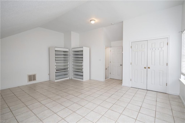 interior space with visible vents, vaulted ceiling, and light tile patterned floors