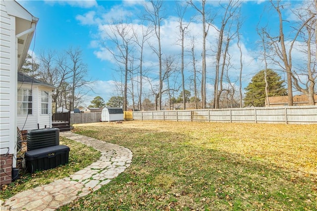 view of yard featuring a fenced backyard, an outdoor structure, central AC, and a storage unit