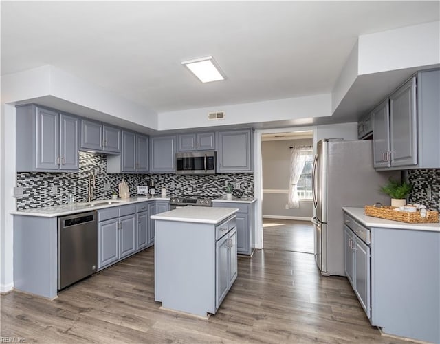 kitchen featuring light wood finished floors, visible vents, appliances with stainless steel finishes, gray cabinetry, and a sink