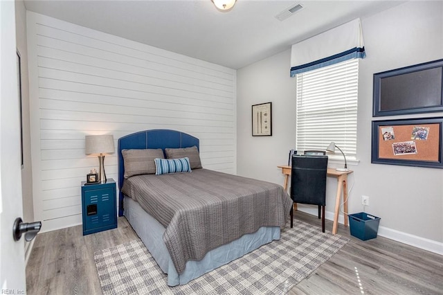 bedroom with wood finished floors, visible vents, and baseboards