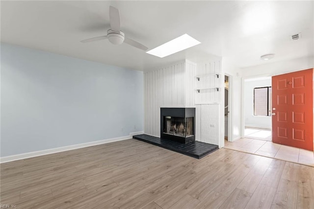 unfurnished living room featuring visible vents, a ceiling fan, a multi sided fireplace, wood finished floors, and baseboards