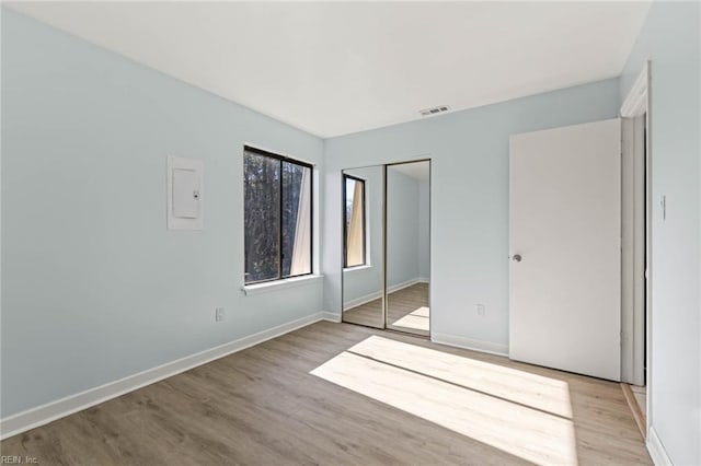 unfurnished bedroom featuring a closet, light wood-type flooring, visible vents, and baseboards