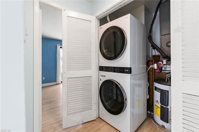 laundry room with laundry area, stacked washer and dryer, light wood-style flooring, and electric water heater