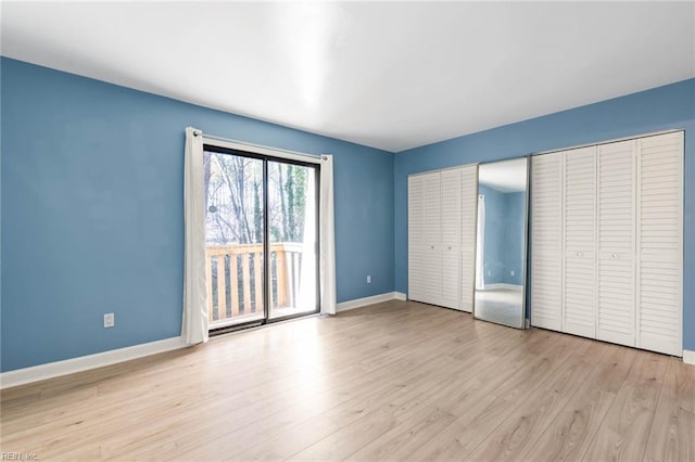 unfurnished bedroom with access to exterior, light wood-style flooring, and baseboards