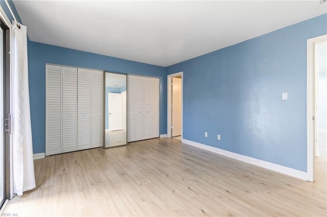 unfurnished bedroom with multiple closets, baseboards, and wood finished floors