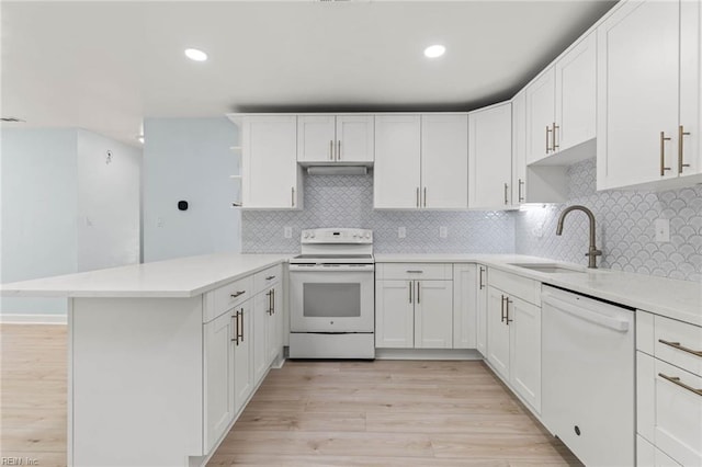 kitchen with a peninsula, white appliances, a sink, light wood-style floors, and open shelves