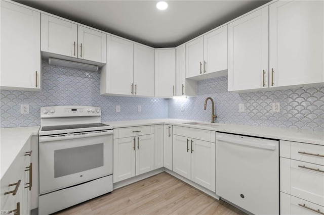 kitchen with white appliances, a sink, light countertops, light wood-type flooring, and decorative backsplash