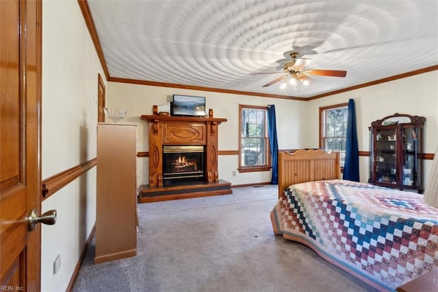 carpeted bedroom with baseboards, crown molding, and a glass covered fireplace