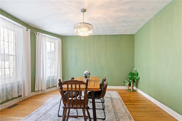 dining space featuring an inviting chandelier, visible vents, baseboards, and wood finished floors