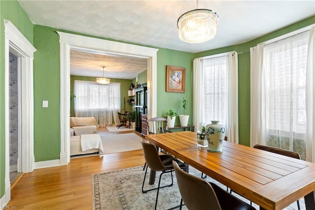 dining space featuring baseboards, light wood-style floors, and an inviting chandelier