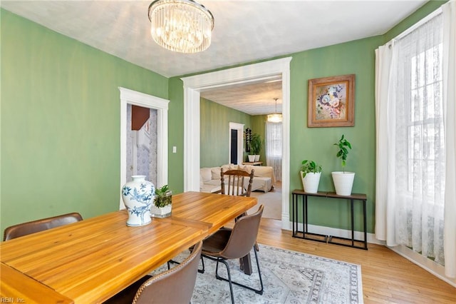 dining room featuring a chandelier, light wood-style floors, and baseboards