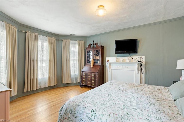 bedroom featuring ornamental molding and wood finished floors