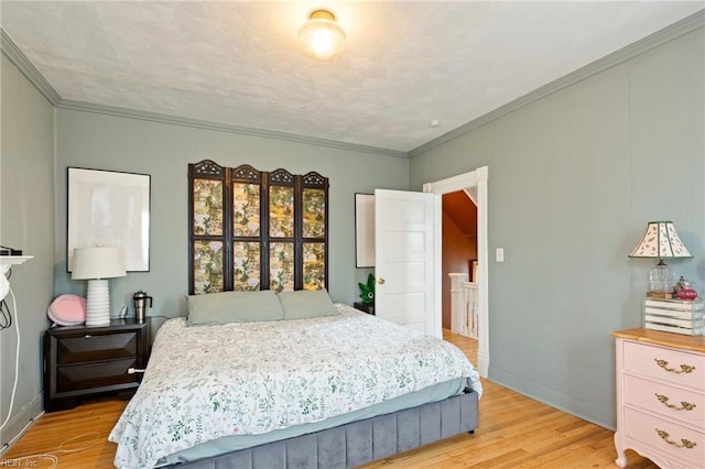 bedroom featuring crown molding, light wood-style flooring, and baseboards